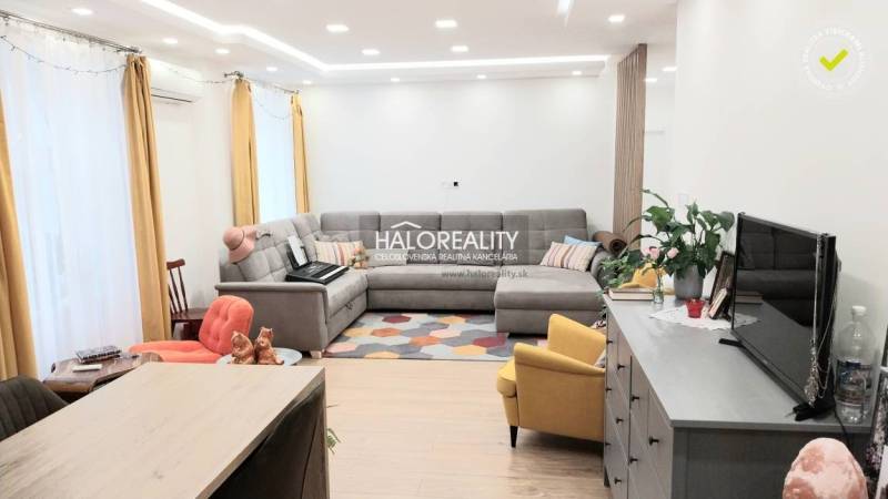 Wohnzimmer in einer 3-Zimmer-Wohnung mit Holzboden, grauem Sofa und gelbem Sessel.