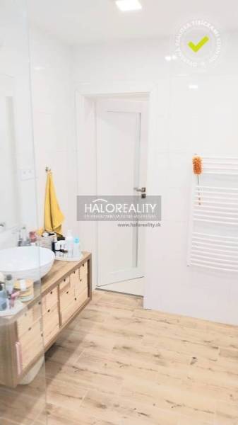 Badezimmer mit Holzboden, Waschbecken auf der Arbeitsplatte und weißen Wänden in einer 3-Zimmer-Wohnung.