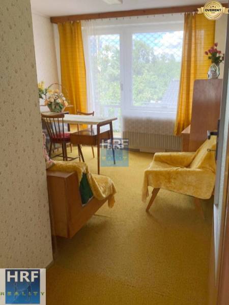 Ein Zimmer in einem Einfamilienhaus mit einem Sessel, einem Tisch und einem gelben Teppich.