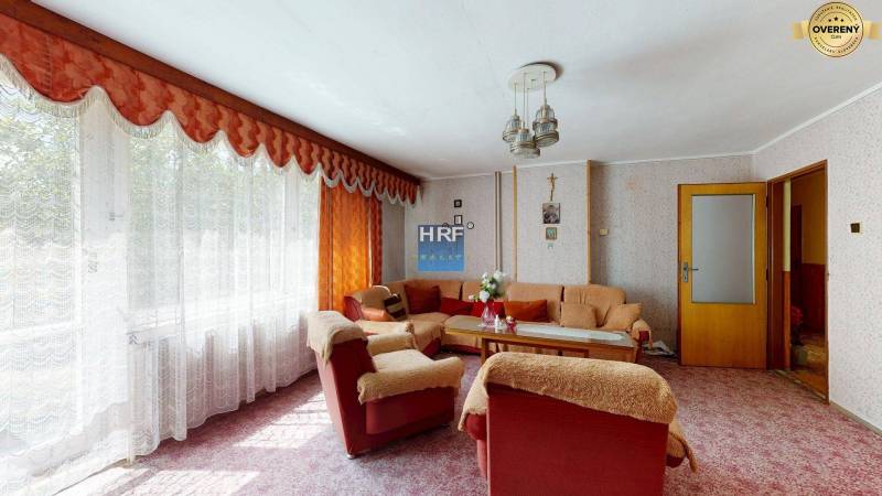 Wohnzimmer in einem Einfamilienhaus mit Blumenmuster-Tapete, weichem Sofa und langen Vorhängen.
