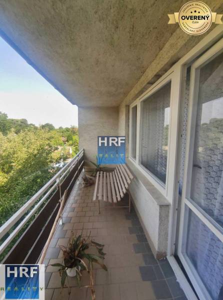 Balkon eines Einfamilienhauses mit einer Holzbank, einer Pflanze und Blick auf den Garten in Radošovce.