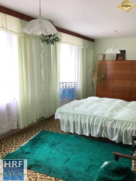 Schlafzimmer im Einfamilienhaus mit Teppichen, Vorhängen und einem Holzschrank.