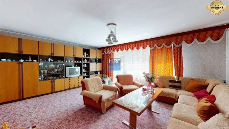 Wohnzimmer in einem Einfamilienhaus mit Sitzgarnitur, Wohnwand und Blumen.