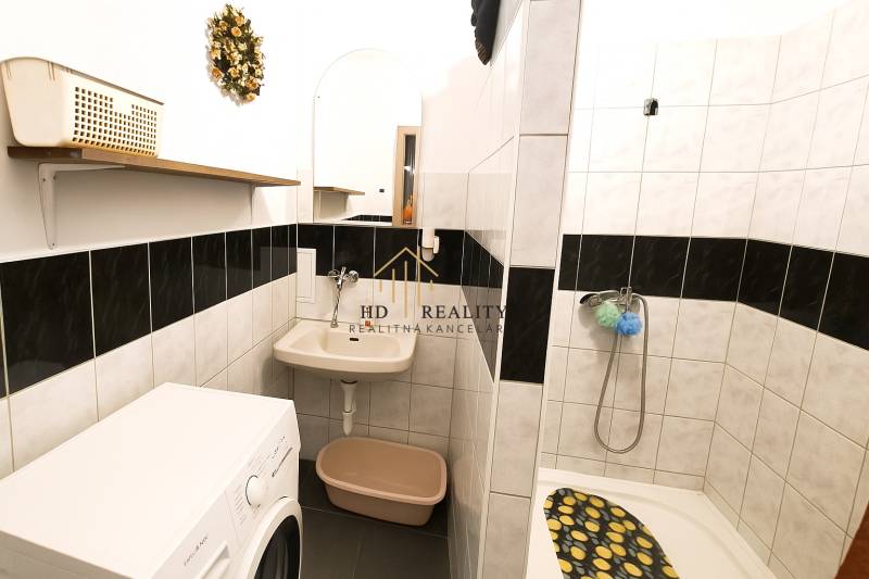 Badezimmer mit Waschmaschine, Dusche und Waschbecken in einer 2-Zimmer-Wohnung.