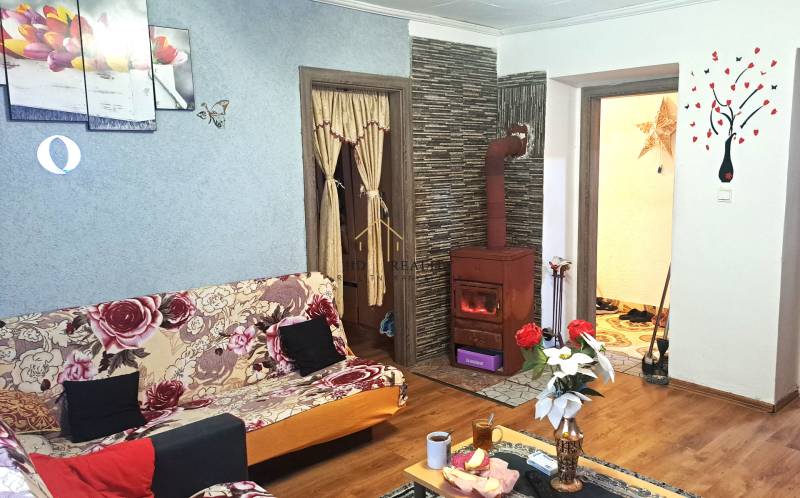 Wohnzimmer in einer 2-Zimmer-Wohnung mit Kachelofen und Boden in Holzoptik.