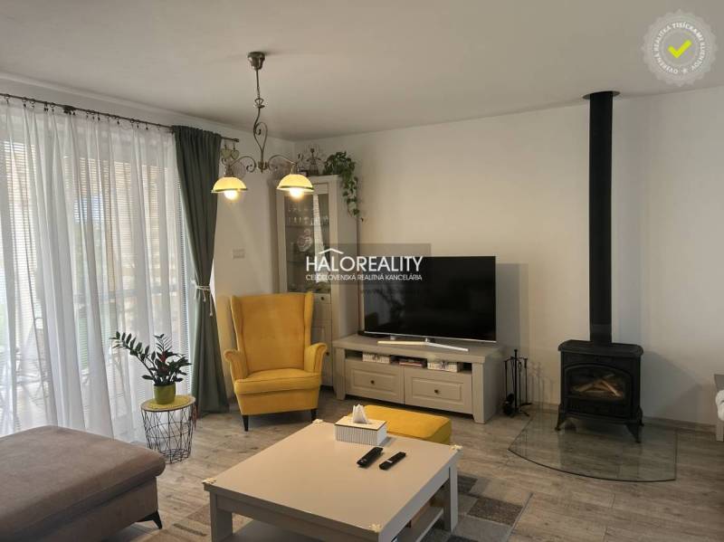 Wohnzimmer in einem Einfamilienhaus mit Kamin, gelbem Sessel und Fernseher.