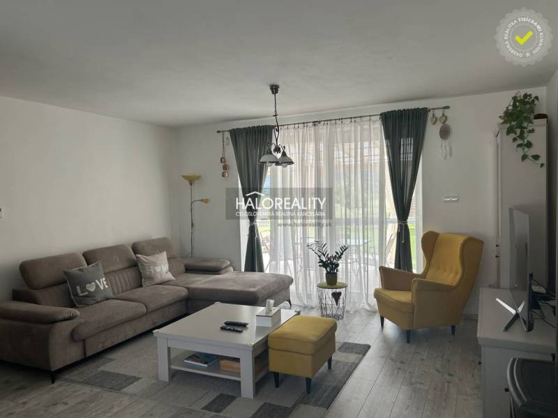 Wohnzimmer in einem Einfamilienhaus mit einem bequemen Sofa und einem gelben Sessel.