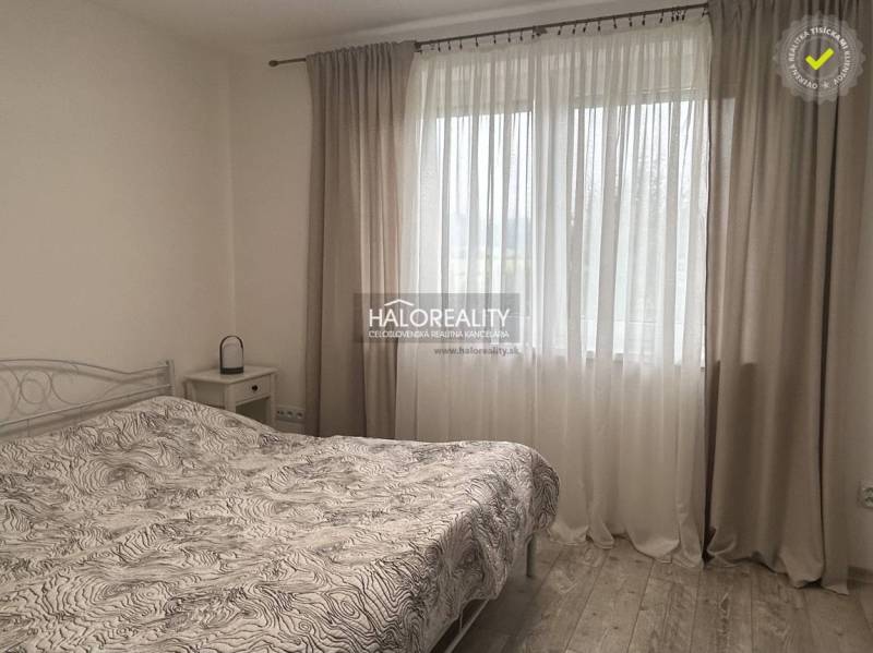 Schlafzimmer mit Bett und Vorhängen in einem Einfamilienhaus, helle Atmosphäre.