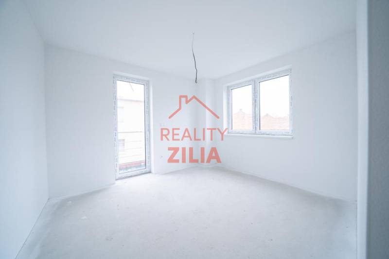 Ein leerer Raum in einem Einfamilienhaus mit weißen Wänden und großen Fenstern.