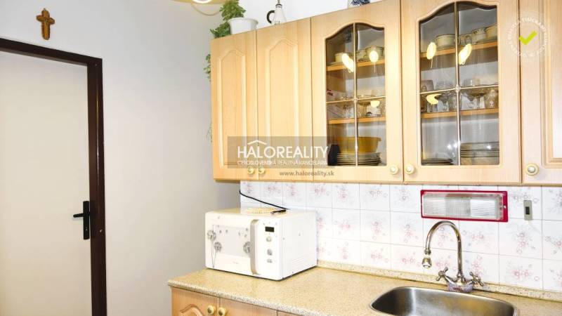 Küche in einer 3-Zimmer-Wohnung mit Schränken, Mikrowelle und Spüle.