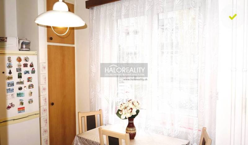 Küche in einer 3-Zimmer-Wohnung mit einem Kühlschrank und einem Tisch, auf dem Blumen in einer Vase stehen.