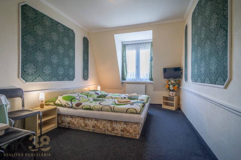 Ein Zimmer mit einem Doppelbett, Teppichboden, Fernseher, Stuhl und Dekorationen in Hotels und Pensionen.