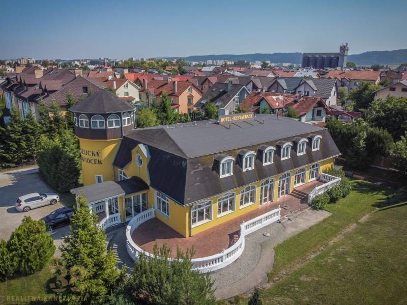 Gelbes Hotel mit Turm, umgeben von einem Garten in der Stadt Poprad, Hotels und Pensionen.