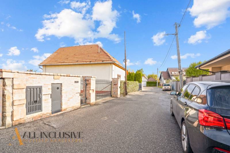 Ein Einfamilienhaus in der Kúpeľná-Straße in Dunajská Streda, umgeben von Autos und einem Zaun.