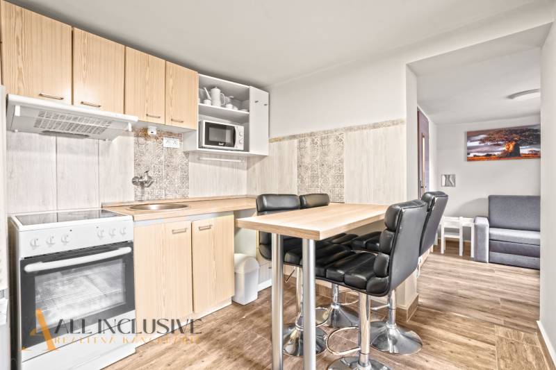 Küche in einem Einfamilienhaus mit Bartisch, schwarzen Stühlen und einem Boden in Holzoptik.