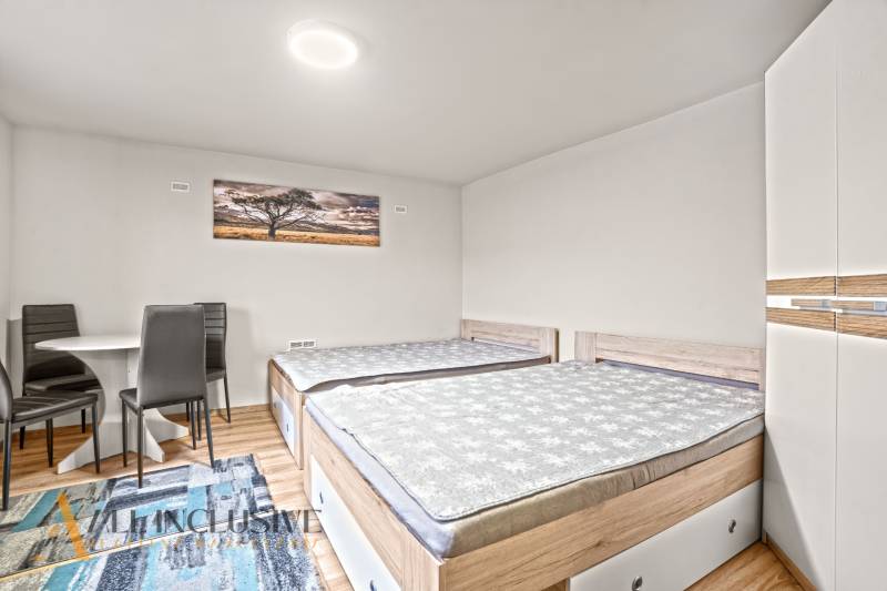 Ein Schlafzimmer in einem Einfamilienhaus mit zwei Betten, einem Schrank und einem Boden mit Holzdekor.