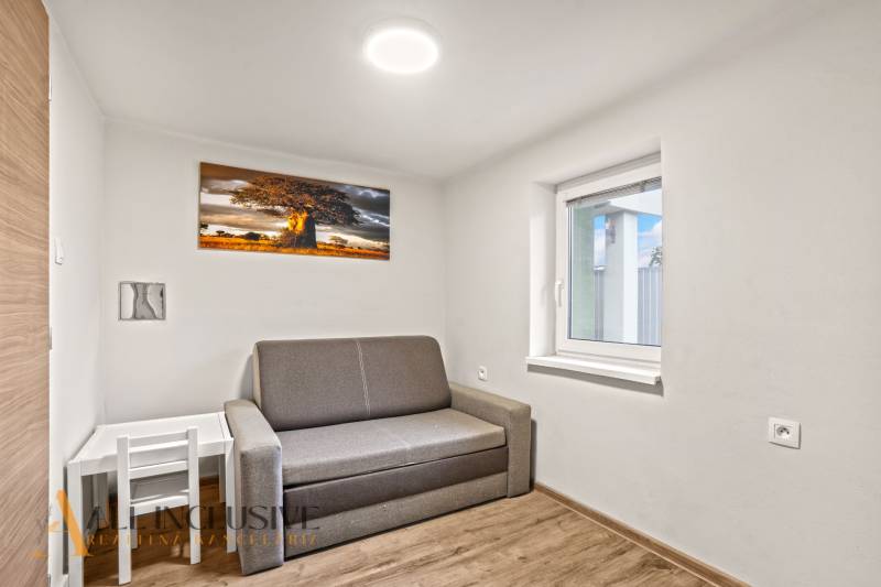 Ein Zimmer eines Einfamilienhauses mit einem Sofa, einem Baumgemälde und einem Boden mit Holzdekor.