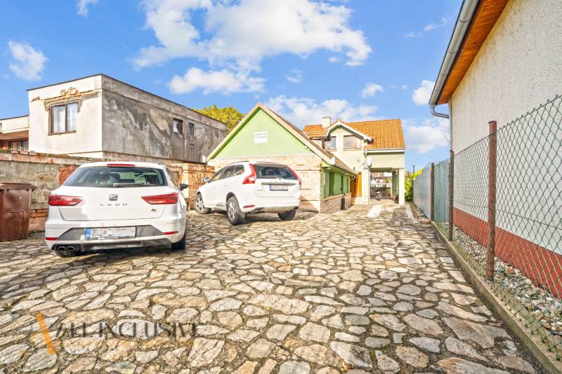 Ein Einfamilienhaus in der Kúpeľná-Straße in Dunajská Streda mit einem gepflasterten Hof und geparkten Autos.