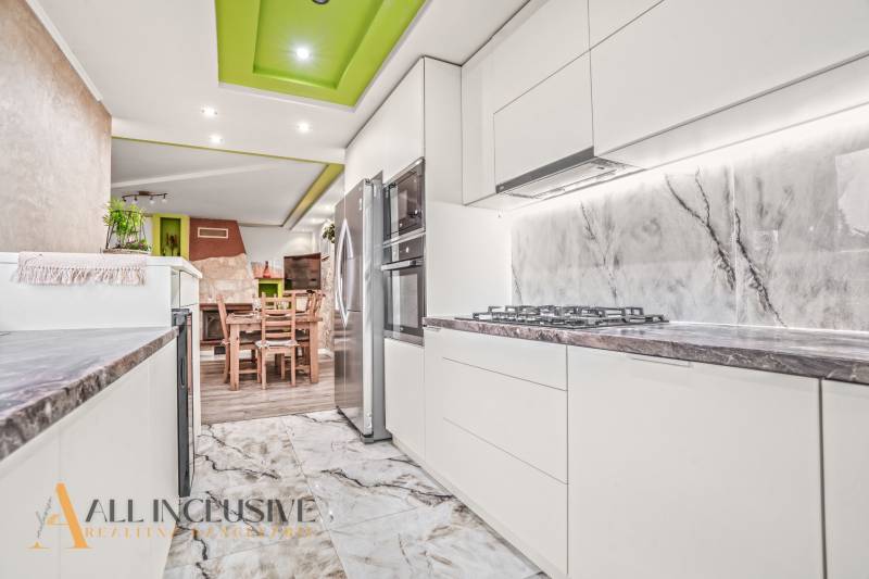 Küche eines Einfamilienhauses mit weißen Schränken, Steinarbeitsplatte und dekorativer Decke.