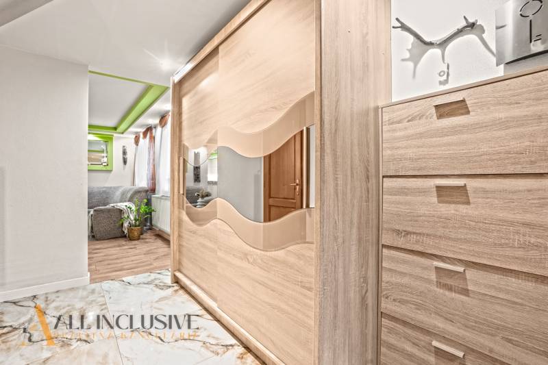 In einem Einfamilienhaus sieht man einen Kleiderschrank mit Spiegel und einen Boden mit Holzdekor.