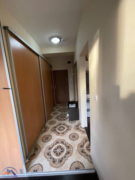 Ein schmaler Flur in einer Einzimmerwohnung mit auffälligen Fliesen und Schiebetüren.