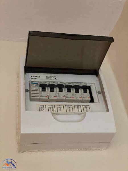 Elektrischer Verteilerkasten mit offenem Deckel und gekennzeichneten Sicherungsautomaten in einer Einzimmerwohnung.