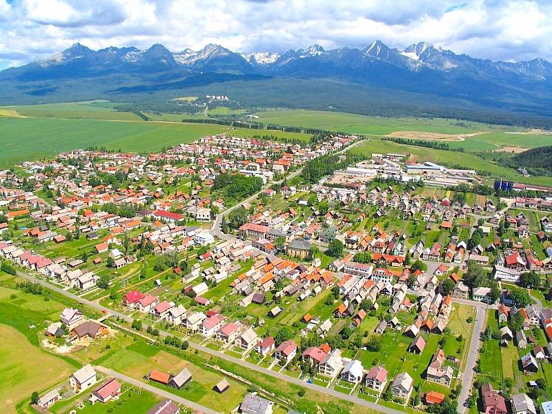 Luftaufnahme von landwirtschaftlichen und forstwirtschaftlichen Flächen in Štrba mit der Hohen Tatra im Hintergrund.