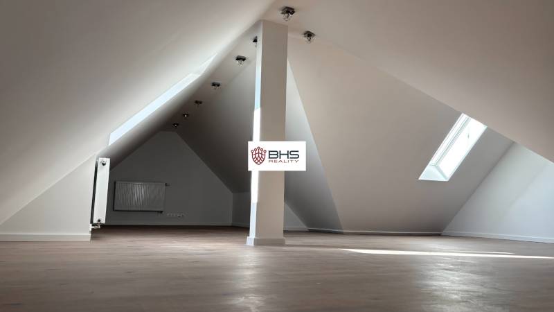 Dachboden in einer 3-Zimmer-Wohnung mit Fenster und Boden in Holzoptik.