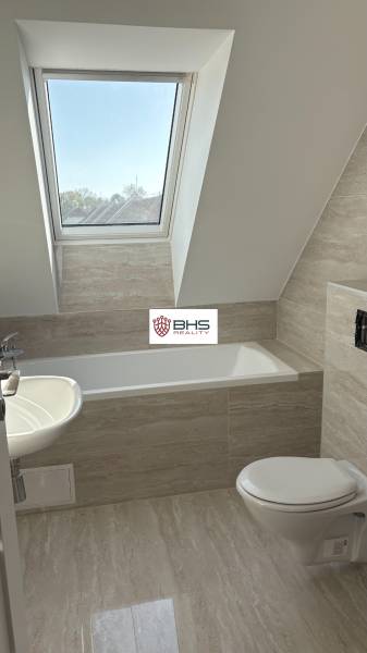 Badezimmer in einer 3-Zimmer-Wohnung mit Badewanne und Dachfenster, Boden mit Holzdekor.