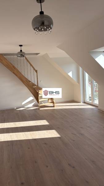 Dachbodenraum in einer 3-Zimmer-Wohnung mit Holzboden und Treppe.