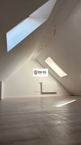 Dachgeschosszimmer mit Holzboden und Dachfenstern in einer 3-Zimmer-Wohnung.