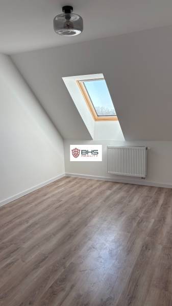 Dachgeschosszimmer mit Holzboden und Dachfenster in einer 3-Zimmer-Wohnung.