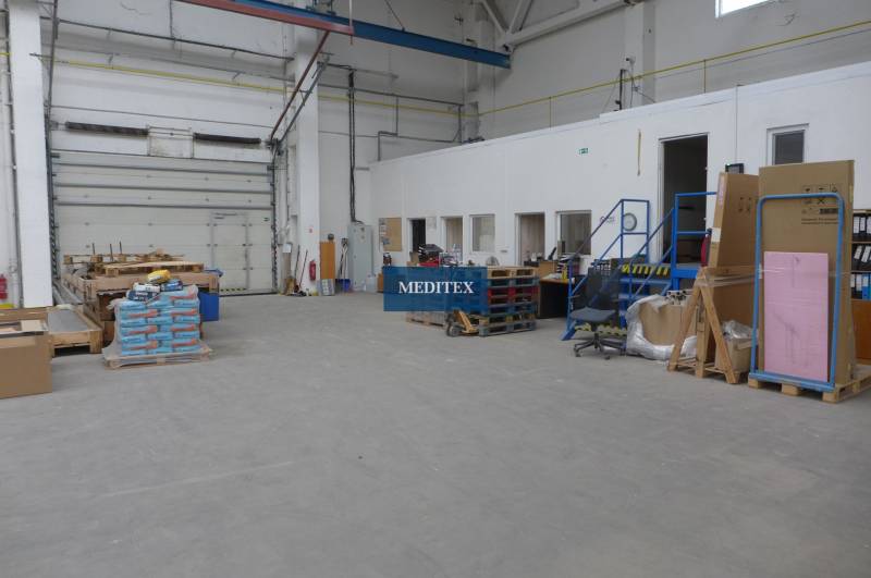 Innenraum eines Lagers mit hohen Decken, Falttoren und verschiedenen Waren auf Paletten.