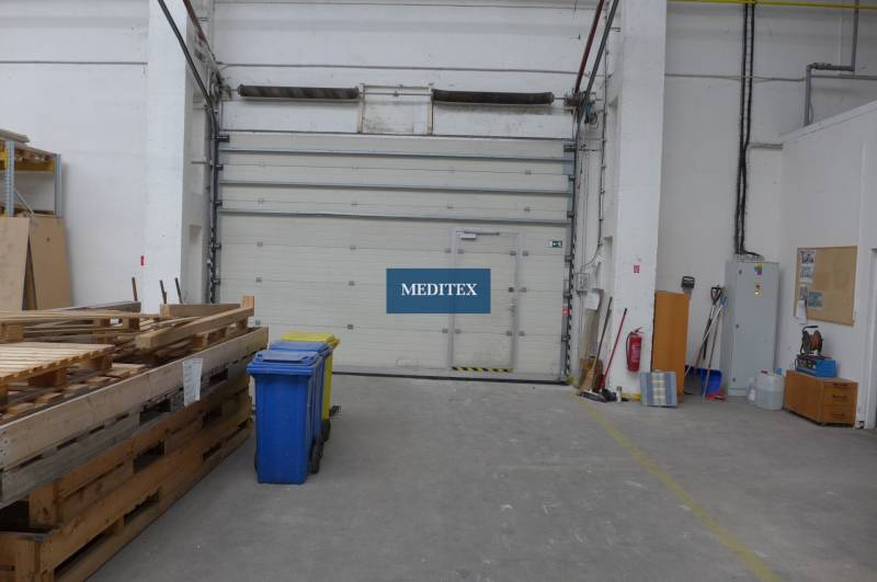 Lagerhäuser und Hallen mit Paletten, Containern und großen Türen.