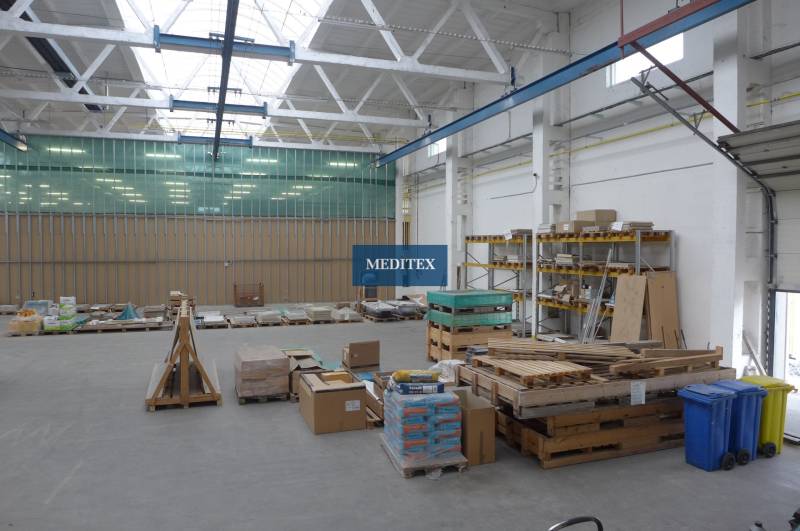 Im Lager befinden sich Paletten mit Baumaterial und Regale mit gelagerten Platten.