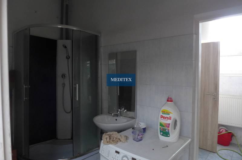 Badezimmer mit Waschmaschine, Duschkabine und Waschmitteln.