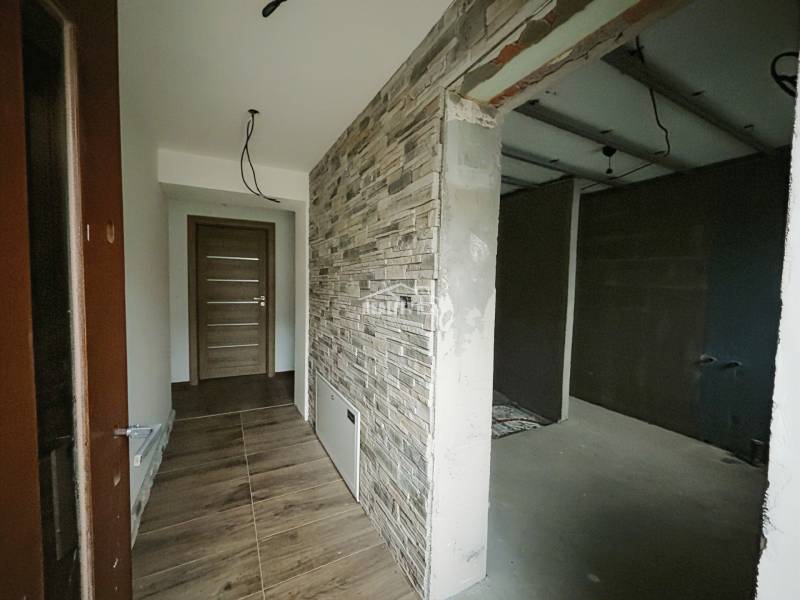 Ein Flur mit einer Wand in Steinoptik und einem Boden in Holzoptik in einem Einfamilienhaus.