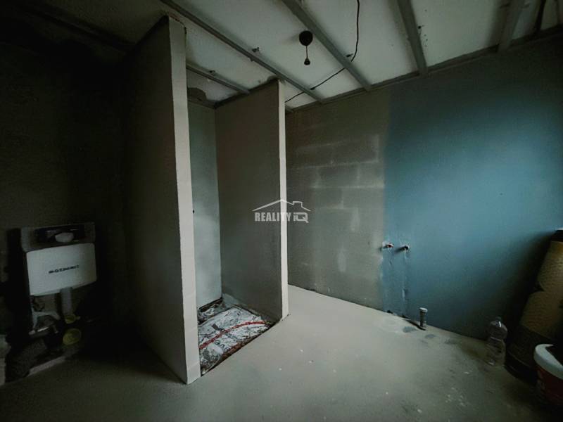 Innenraum eines Einfamilienhauses mit unfertigem Badezimmer und Installationen für WC und Waschbecken.