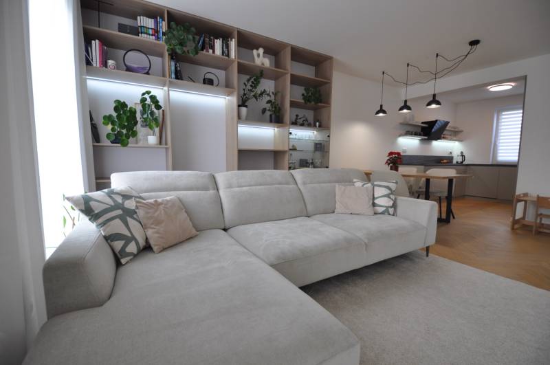 Wohnzimmer mit großem Sofa, Bücherregal und Küchenzeile in einem Einfamilienhaus.