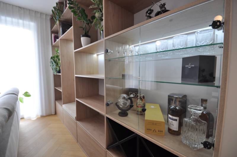 Innenraum eines Einfamilienhauses mit einem Schrank, Glasregalen und einem Boden mit Holzdekor.