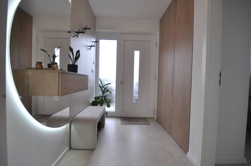 Eingangsbereich in einem Einfamilienhaus mit großem Spiegel und Stauraum.