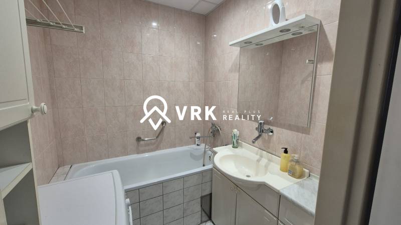 Badezimmer mit Badewanne, Waschbecken und Spiegel in einer 3-Zimmer-Wohnung.