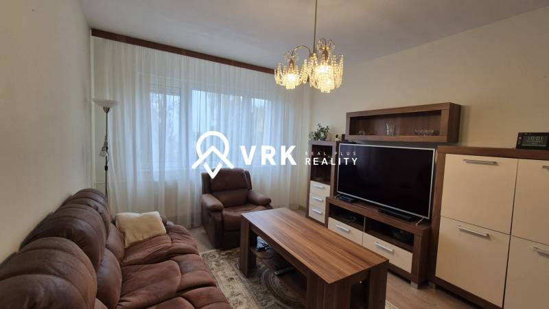 Wohnzimmer mit bequemer Couch, Sessel, Fernseher und Schrank in einer 3-Zimmer-Wohnung.