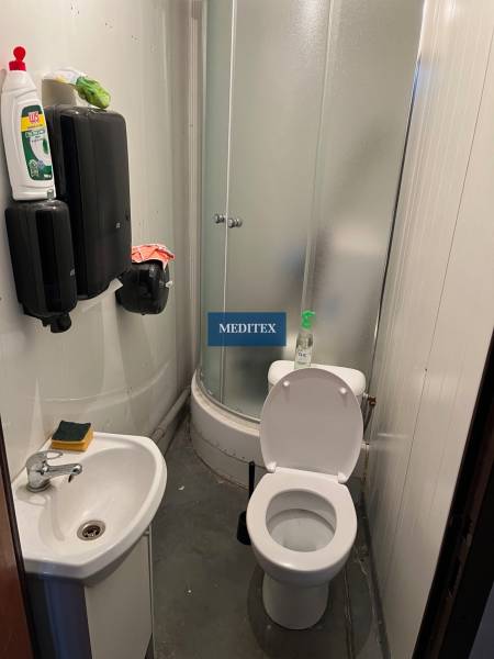 Kleines Badezimmer mit Dusche, Waschbecken und Toilette in Lagerhäusern und Hallen.