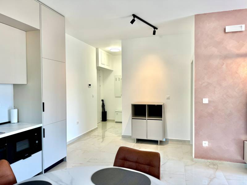 Innenraum einer Einzimmerwohnung mit Küchenzeile, Esstisch und hellen Wänden.