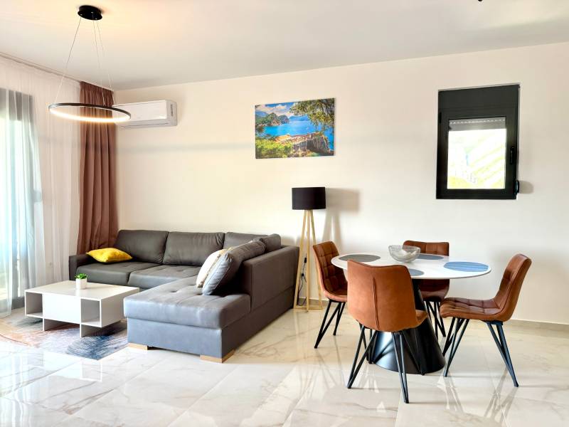 Wohnzimmer in einer Einzimmerwohnung mit Holzboden, Sofa und Esstisch.