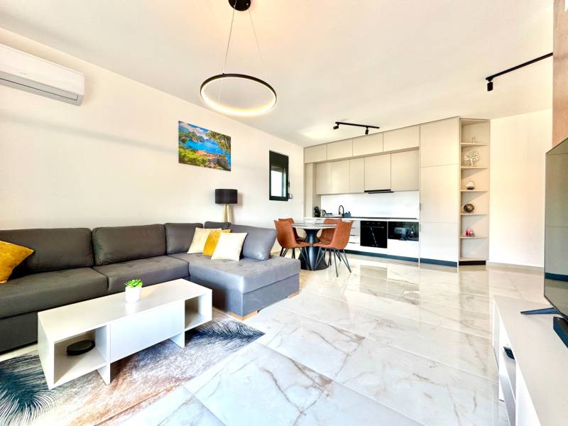 Innenraum einer 1-Zimmer-Wohnung mit Sofa, Kochnische und Esstisch.