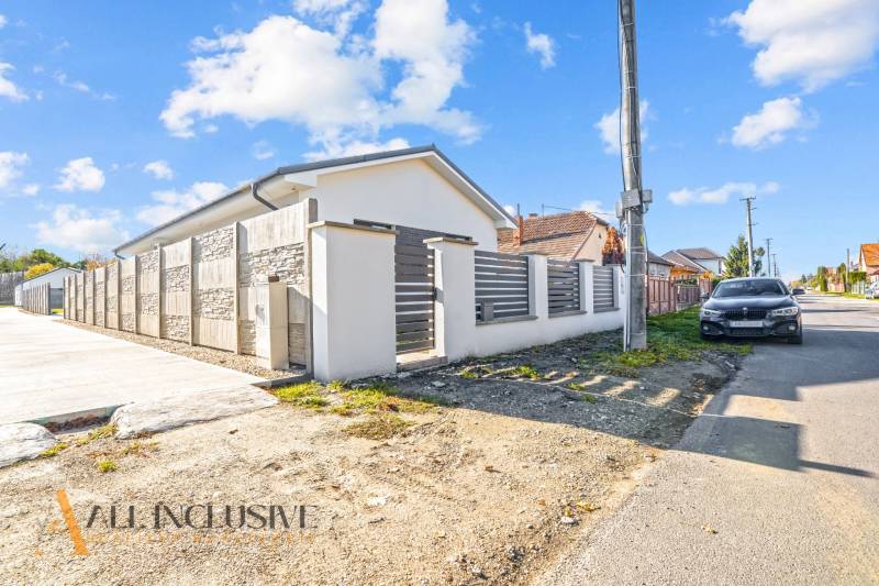 Ein Einfamilienhaus in Orechová Potôň mit einer Steinmauer und einem geparkten Auto auf der Straße.