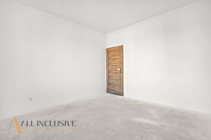 Ein leerer Raum in einem Einfamilienhaus mit weißen Wänden und einer Tür mit Holzdekor.