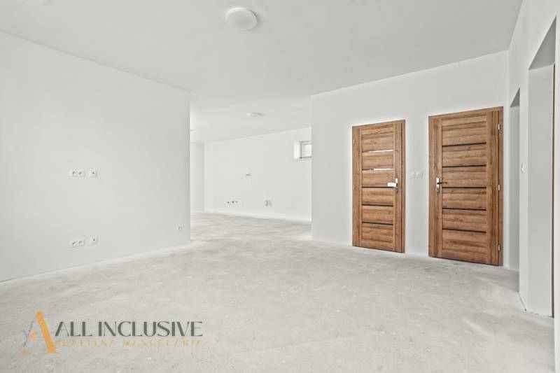 Weiße Wände und Holztüren im Inneren eines Einfamilienhauses mit einem Boden ohne Dekor.